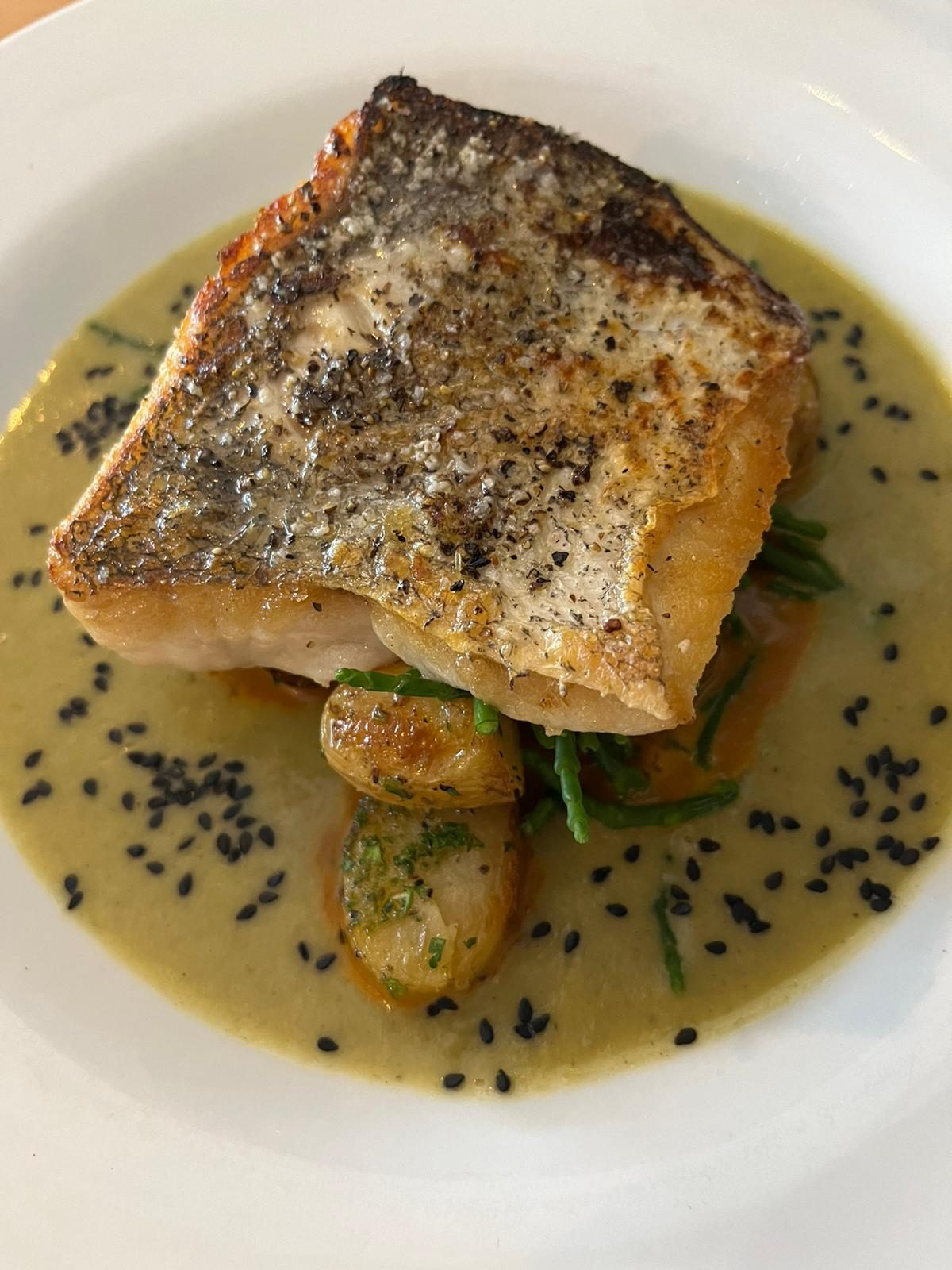 A crispy-skin fish fillet with potatoes in a light sauce